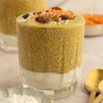 Carrot cake chia pudding topped with coconut, raisins, grated carrots, and pecans.