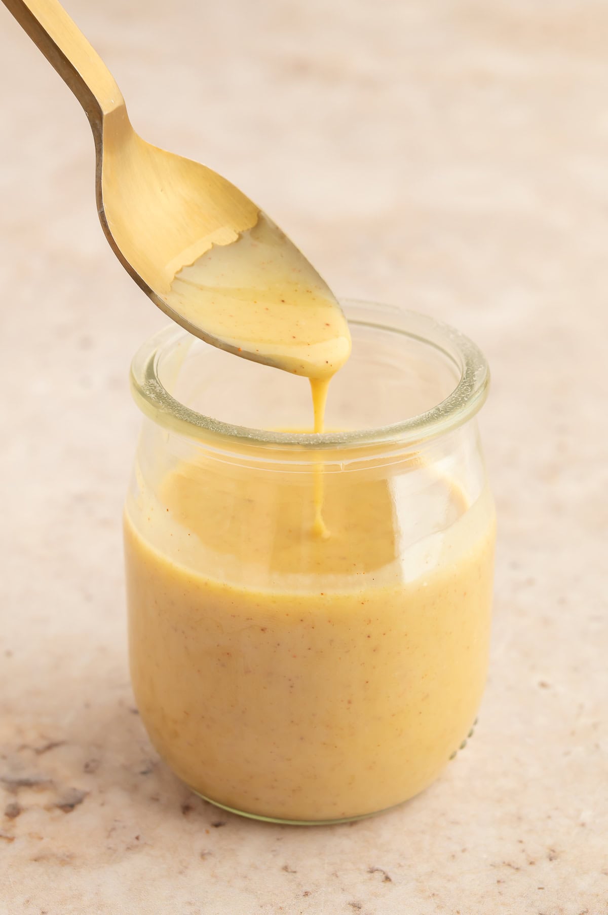 Maple mustard dip in jar with a spoon drizzling some in.
