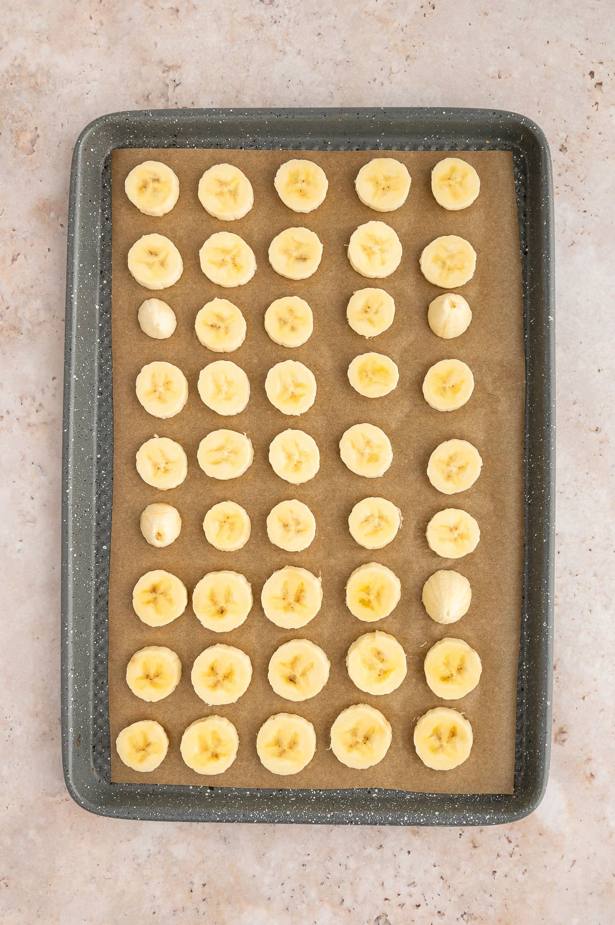 Sliced frozen bananas on a sheet pan.
