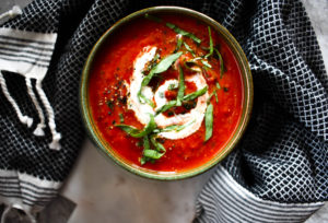 Rich colored tomato soup in green bowl.