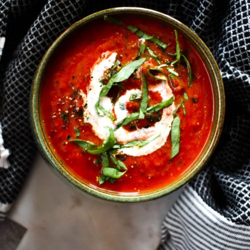 Rich colored tomato soup in green bowl.