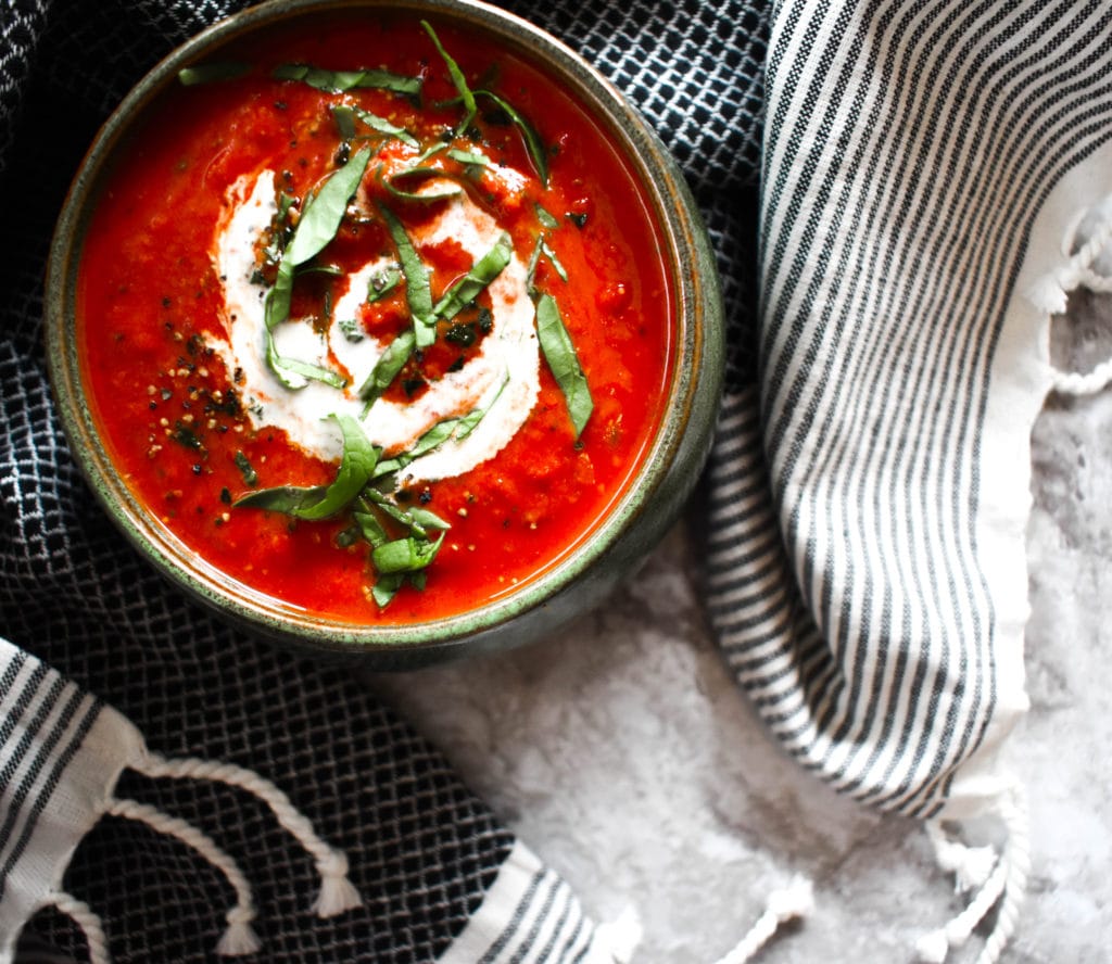 healthy tomato basil soup in a green bowl.