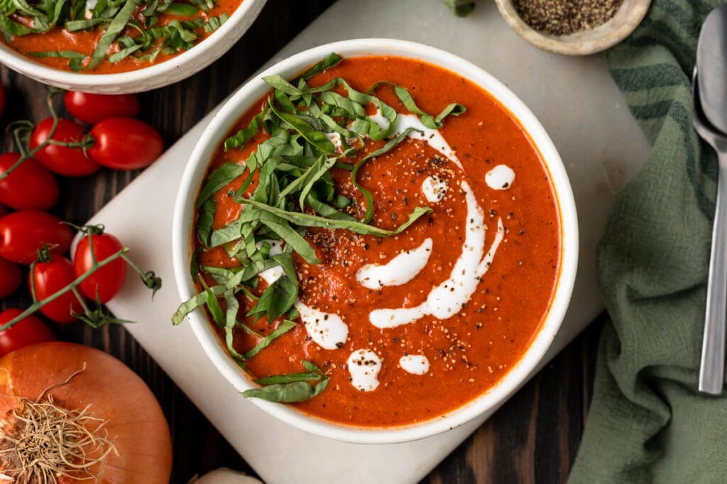 Bowl of healthy paleo tomato soup topped with basil and coconut cream.