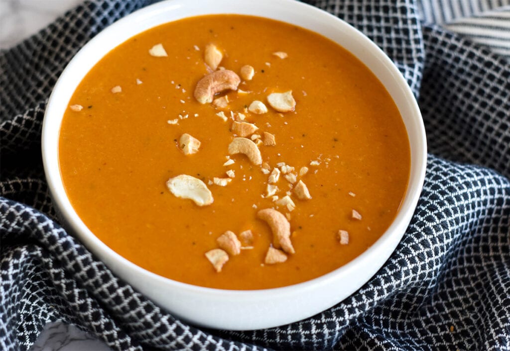 White bowl filled with bright orange curried butternut squash soup.