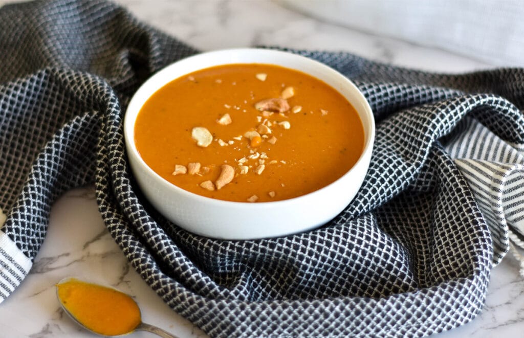 White bowl filled with bright orange curried butternut squash soup.