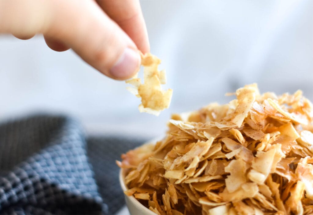 hand grabing coconut chips from bowl