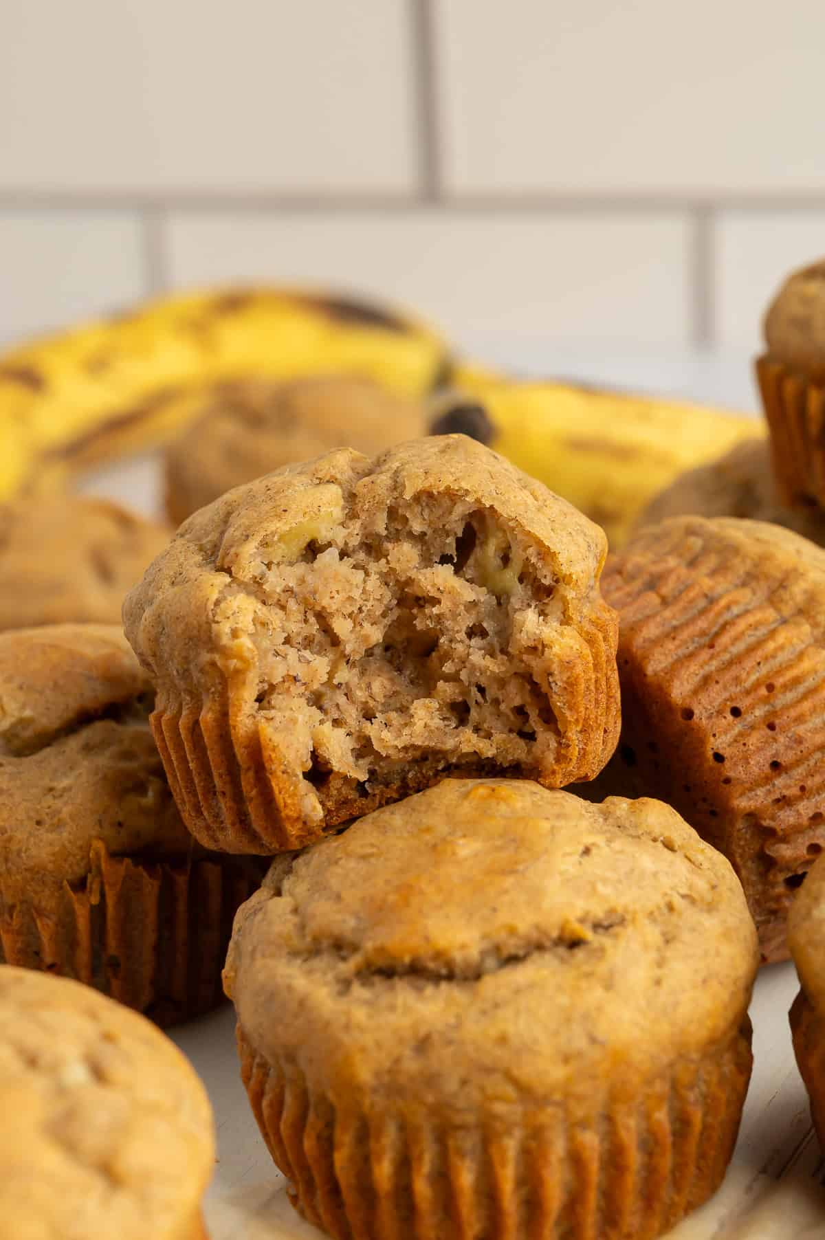 Close up of pile of sugar-free gluten-free banana muffins, one with a bite out of it.