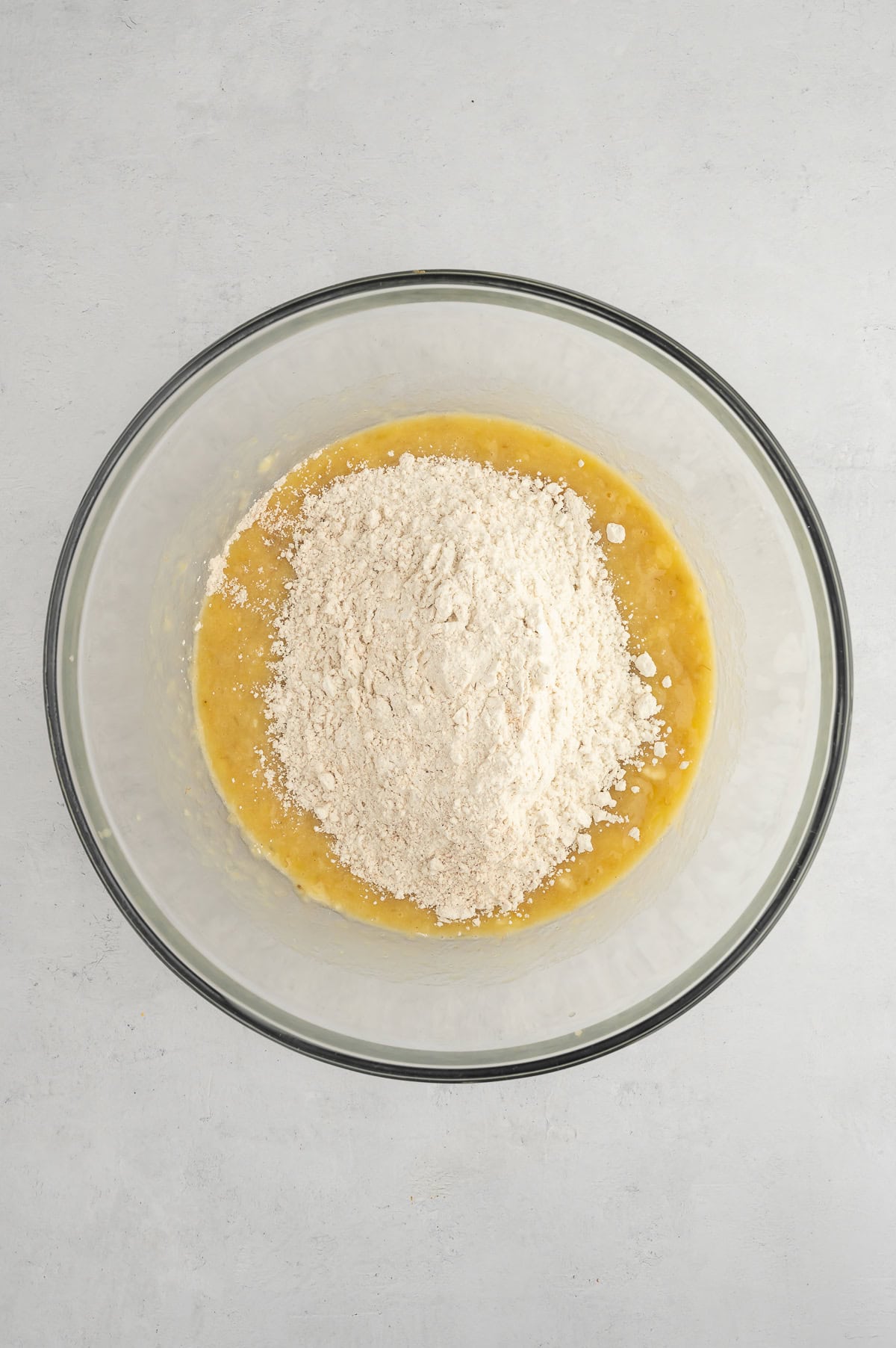 Mixing together wet and dry ingredients for sugar-free gluten-free banana muffins.