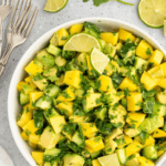 Avocado Mango Cucumber Salad garnished with lime wedges.