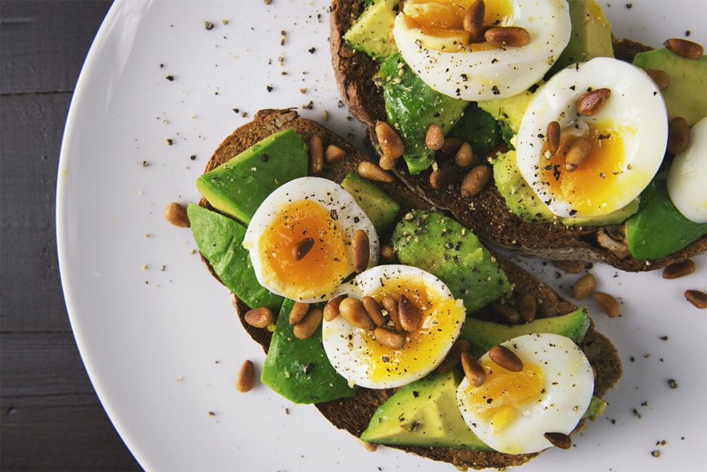 Toast with avocado, soft boiled eggs and pine nuts.