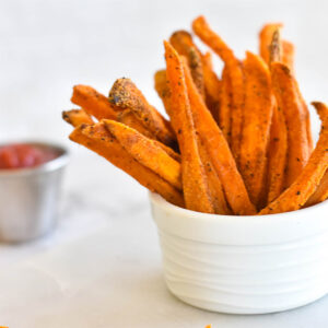 Crispy Paleo Baked Sweet Potato Fries in a bowl next to ketchup.