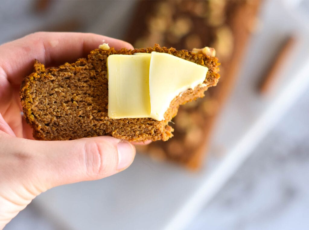 hand holding a piece of keto pumpkin bread with bite out of it