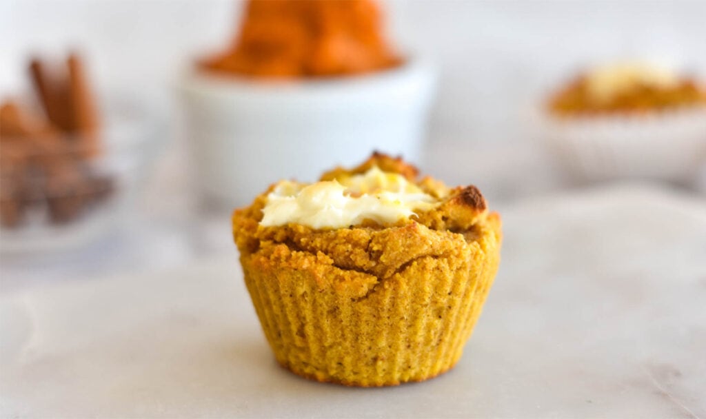 Cream cheese filled muffin with pumpkin in background