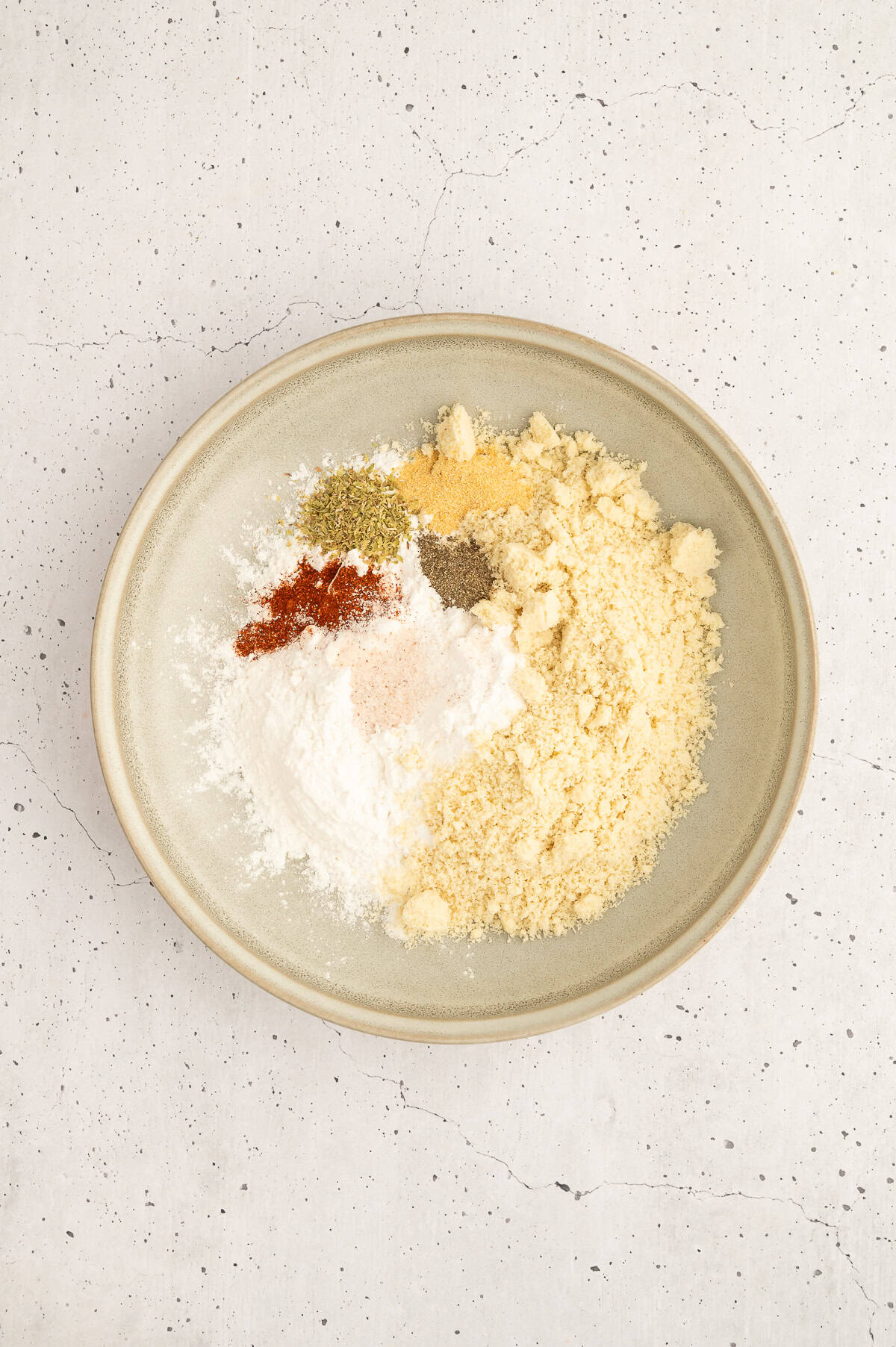 Almond flour, tapioca starch, and seasonings for breading being mixed into a bowl.