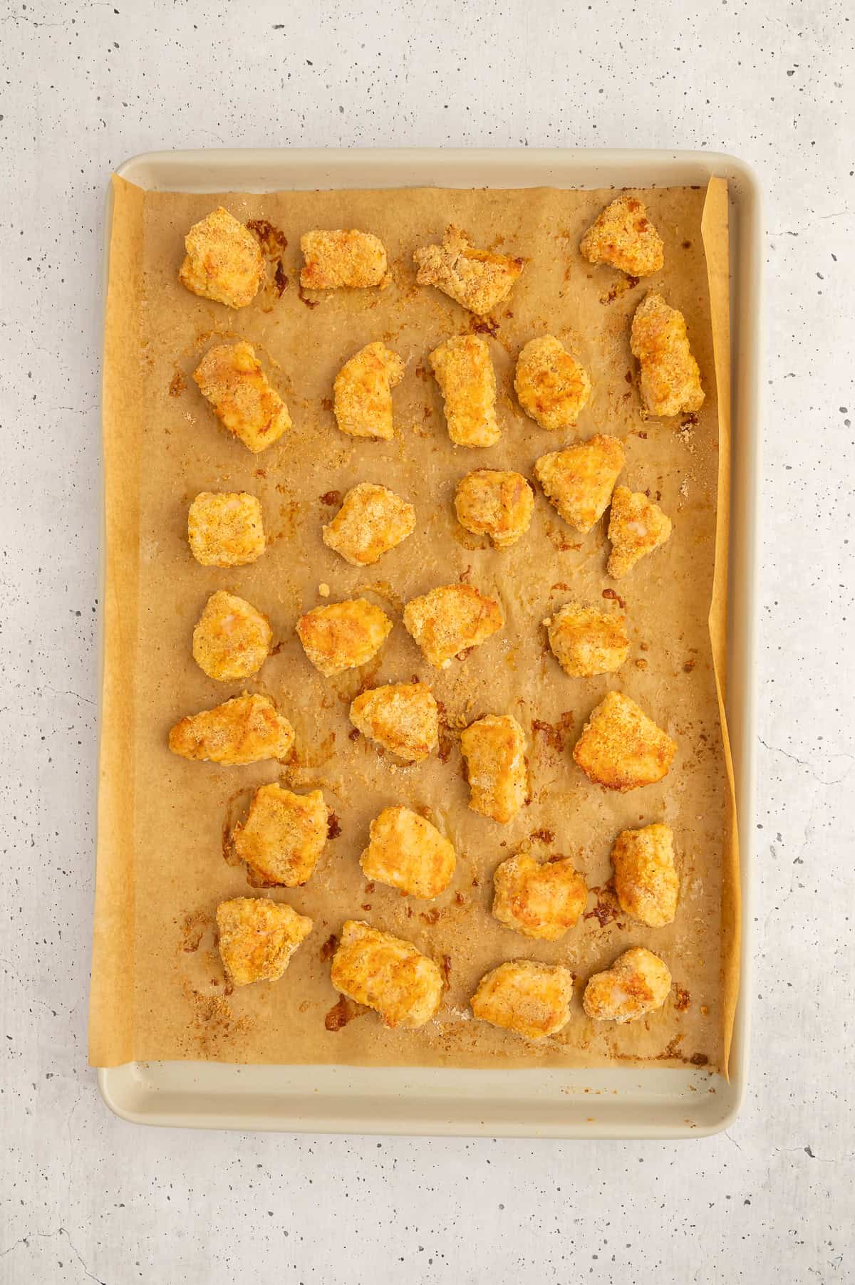 Baked paleo chicken nuggets on a parchment paper lined sheet pan.