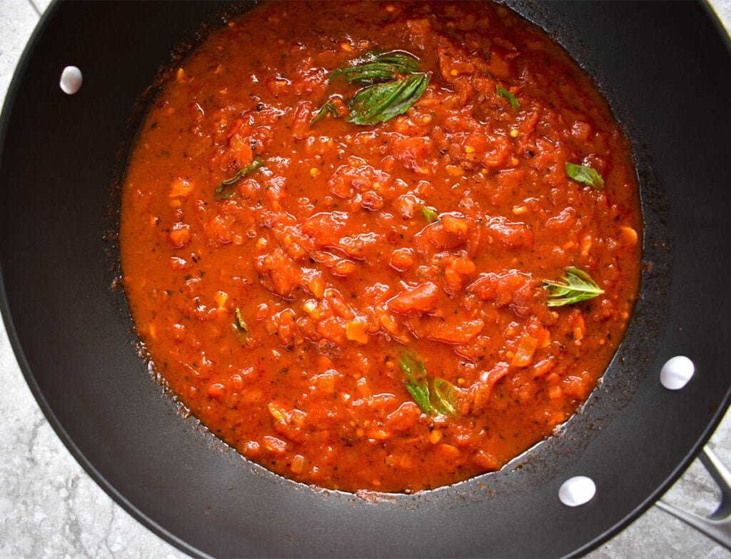 Pan with marinara sauce and basil leaves