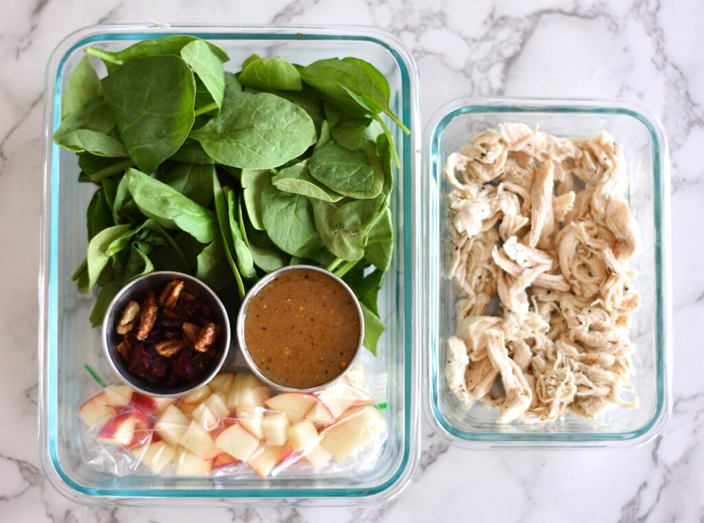 Meal prepped apple salad with apples, pecans, cranberries, spinach and chicken.