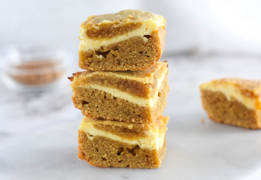 Stack of blonde brownies with cream cheese swirl.