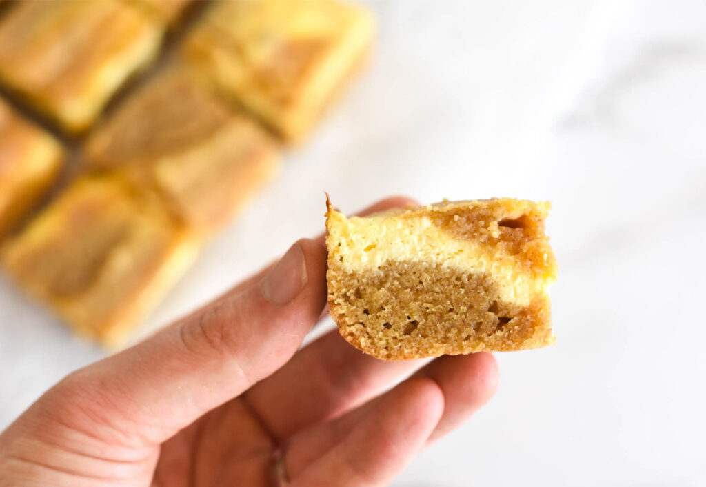 Hand holding keto blondie with cream cheese.