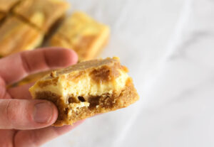 Hand holding keto cream cheese blondie with bite out of it.