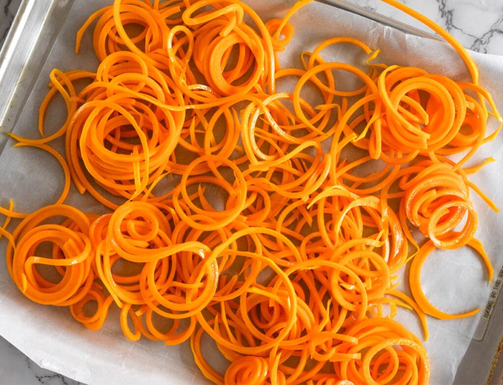 Butternut squash noodles on a sheet pan lined with parchment paper.