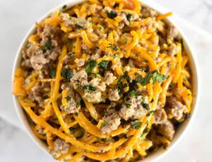 Top down view of butternut squash noodles with sausage and basil.
