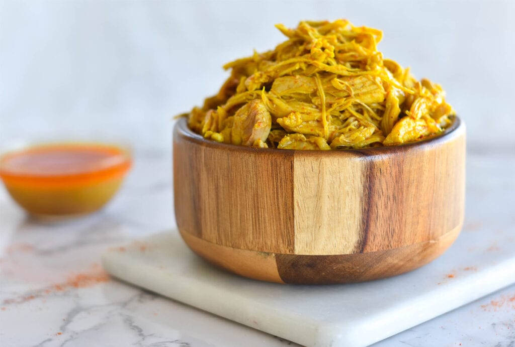 Wooden bowl filled with tandoori chicken curry with white background.