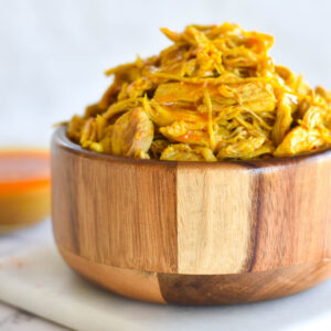 Wooden bowl filled with tandoori chicken curry with white background.