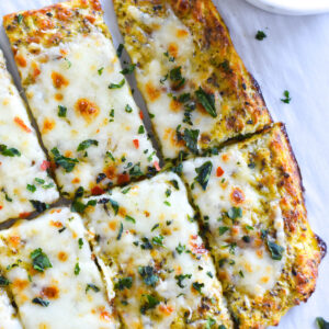 Slices of keto cheesy garlic bread topped with cheese and herbs.