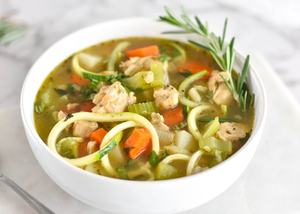 Paleo Chicken Zoodle Soup in a white bowl with carrots, potatoes and chicken breast.