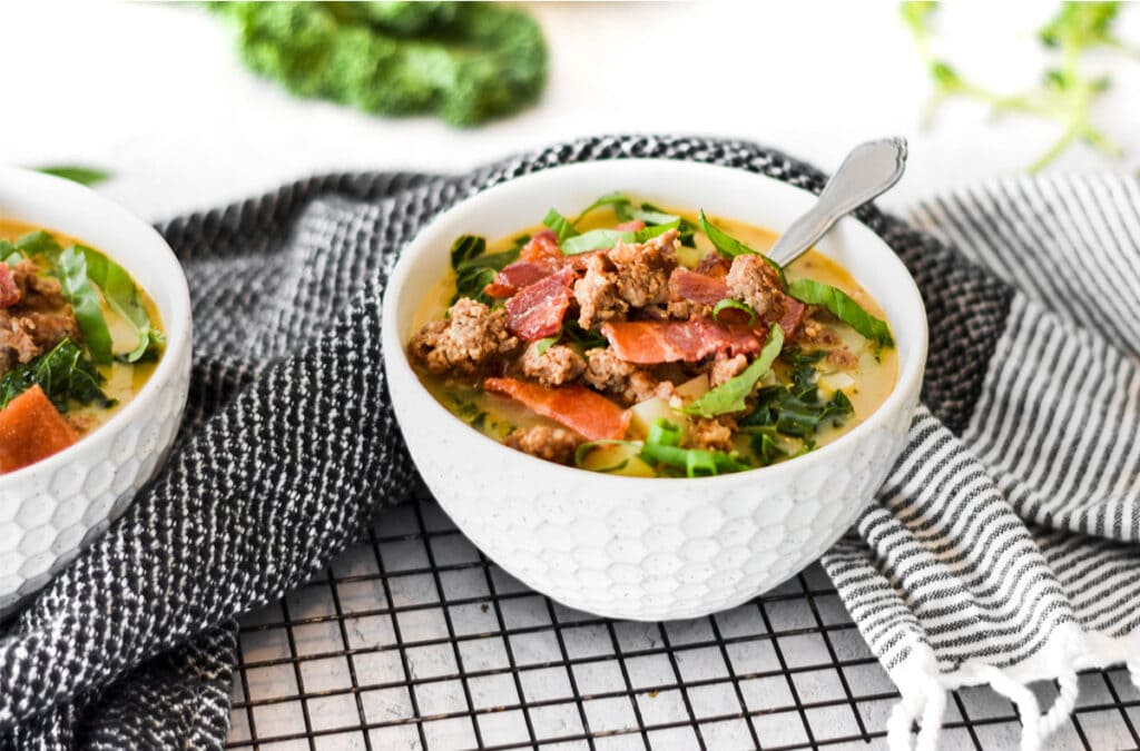 White bowl on a black rack and towel filled with Paleo Whole30 Zuppa Toscana.