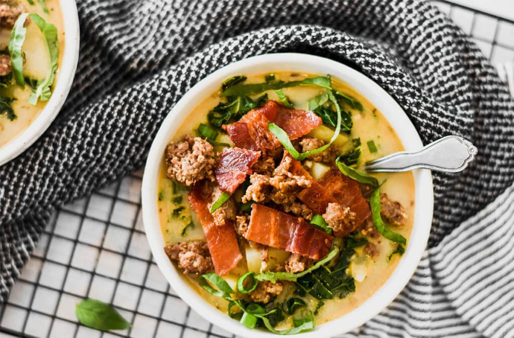 White bowl on a black rack and towel filled with Paleo Whole30 Zuppa Toscana.
