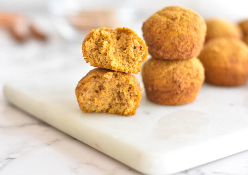 Two stacked donut holes covered in cinnamon coconut sugar, one is broekn open to show a fluffy center.