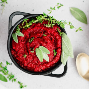 Bowl of bright red AIP nomato sauce with herbs on top.