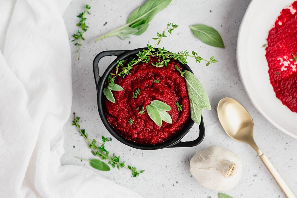 Bowl of bright red AIP nomato sauce with herbs on top.