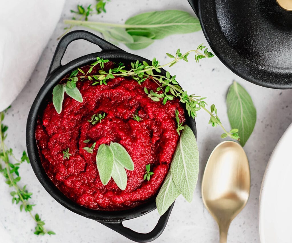 Bowl of bright red nomato sauce with herbs on top.