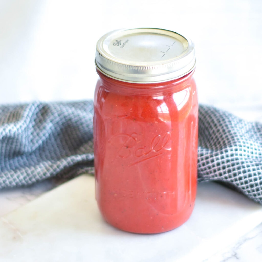 Jar of bright red, nightshade free nomato sauce.