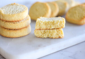 Stack of three golden buttery keto shortbread cookies with one broken in half to show the inside.