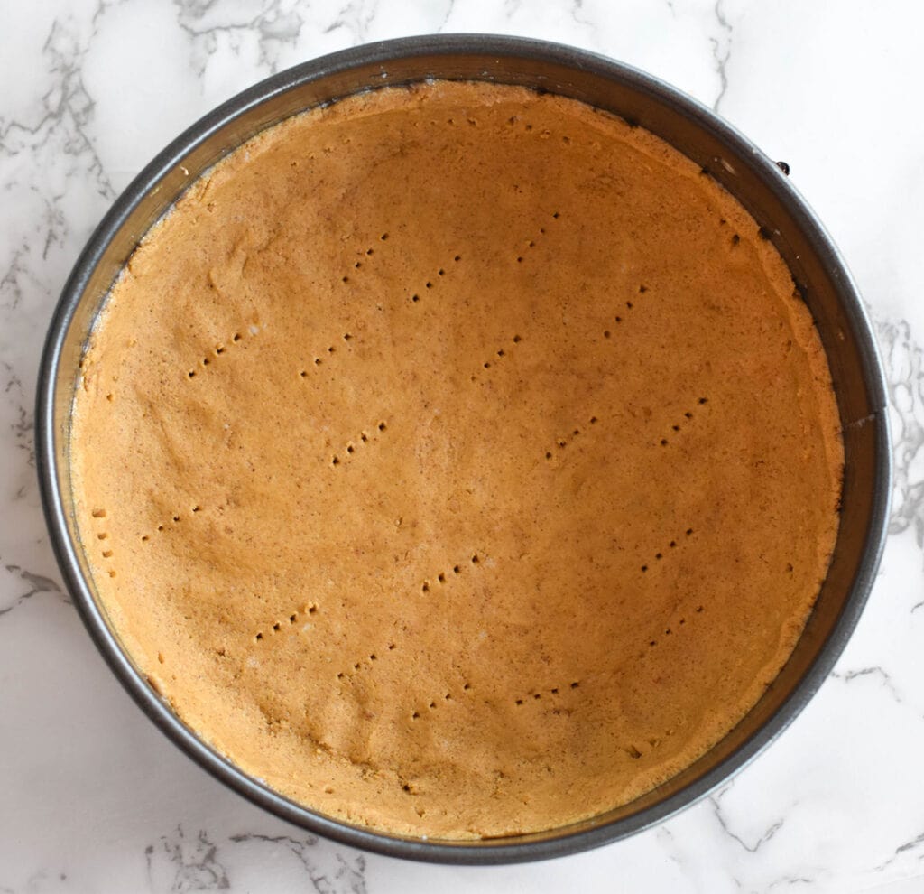 Pumpkin pie crust with fork holes poked in it.