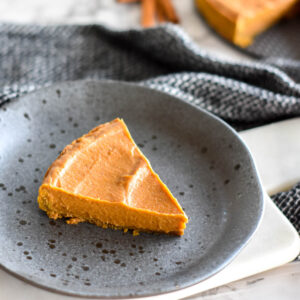 Slice of pumpkin pie on a black stoneware plate.