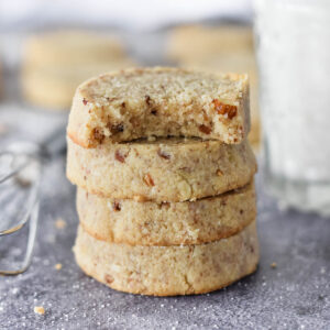 Stack of 4 keto pecan sandies, one with a bite out of it.