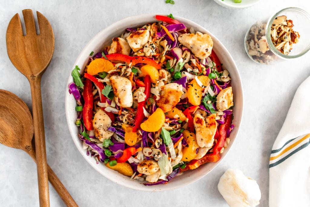 Asian chicken chopped salad with sesame seeds, almonds, cabbage, bell pepepr, cilantro, green onion, chicken and mandarins. 