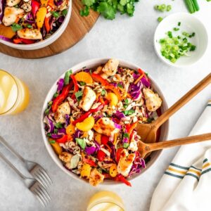 Asian chicken chopped salad with sesame seeds, almonds, cabbage, bell pepepr, cilantro, green onion, chicken and mandarins.