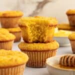 Two almond flour corn muffins stacked, one with a bite out of it.