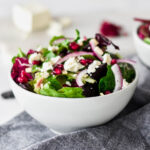 Brightly colored bowls of salad with feta, slivered almond, pomegranate seeds and mixed greens.