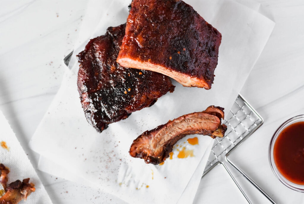 Rack of pellet smoked baby back ribs covered in a sticky looking glaze.