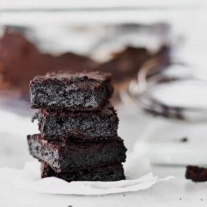 Stack of four dark chocolate paleo brownies.