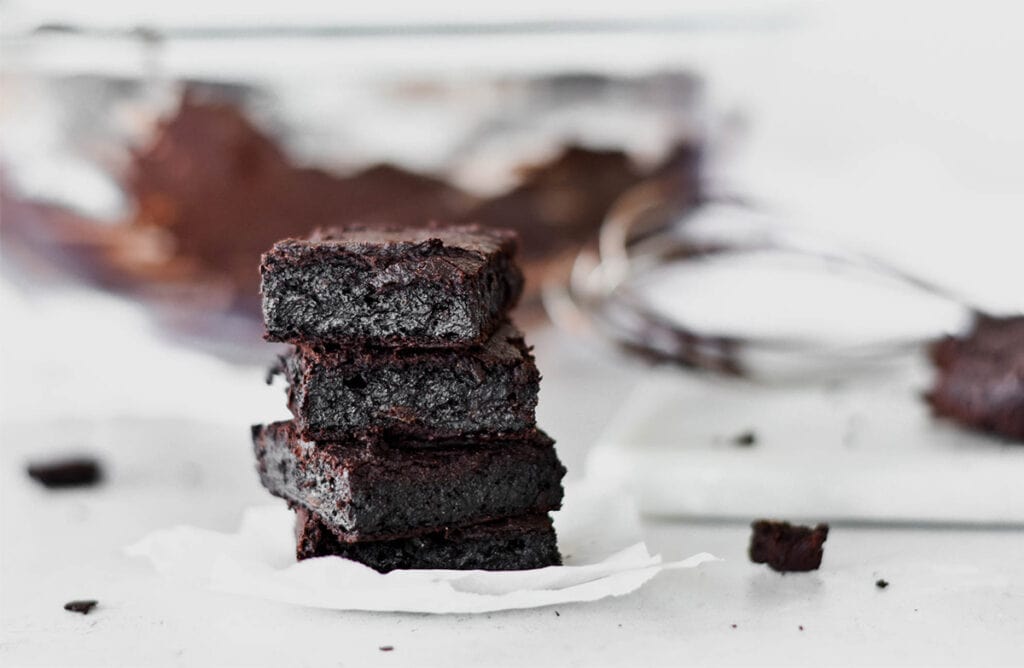 Stack of four dark chocolate paleo brownies.