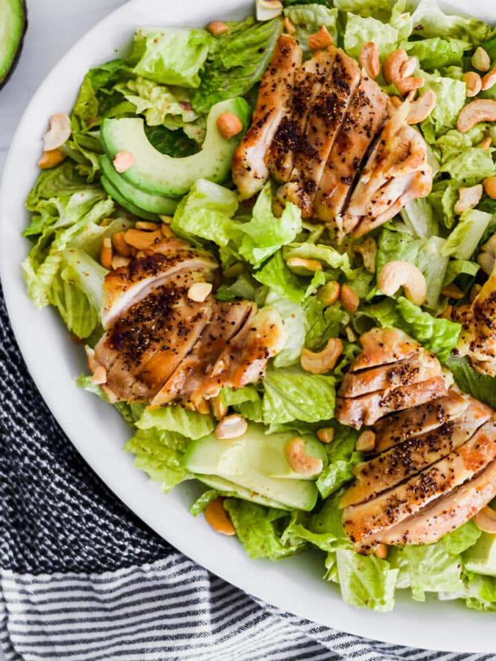 Brightly colored Whole30 Caesar Salad with green romatine lettuce, avocado and chicken.