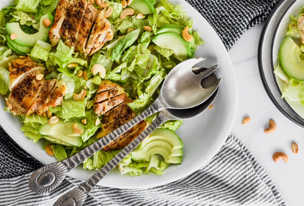 Brightly colored Whole30 Caesar Salad with green romatine lettuce, avocado and chicken.